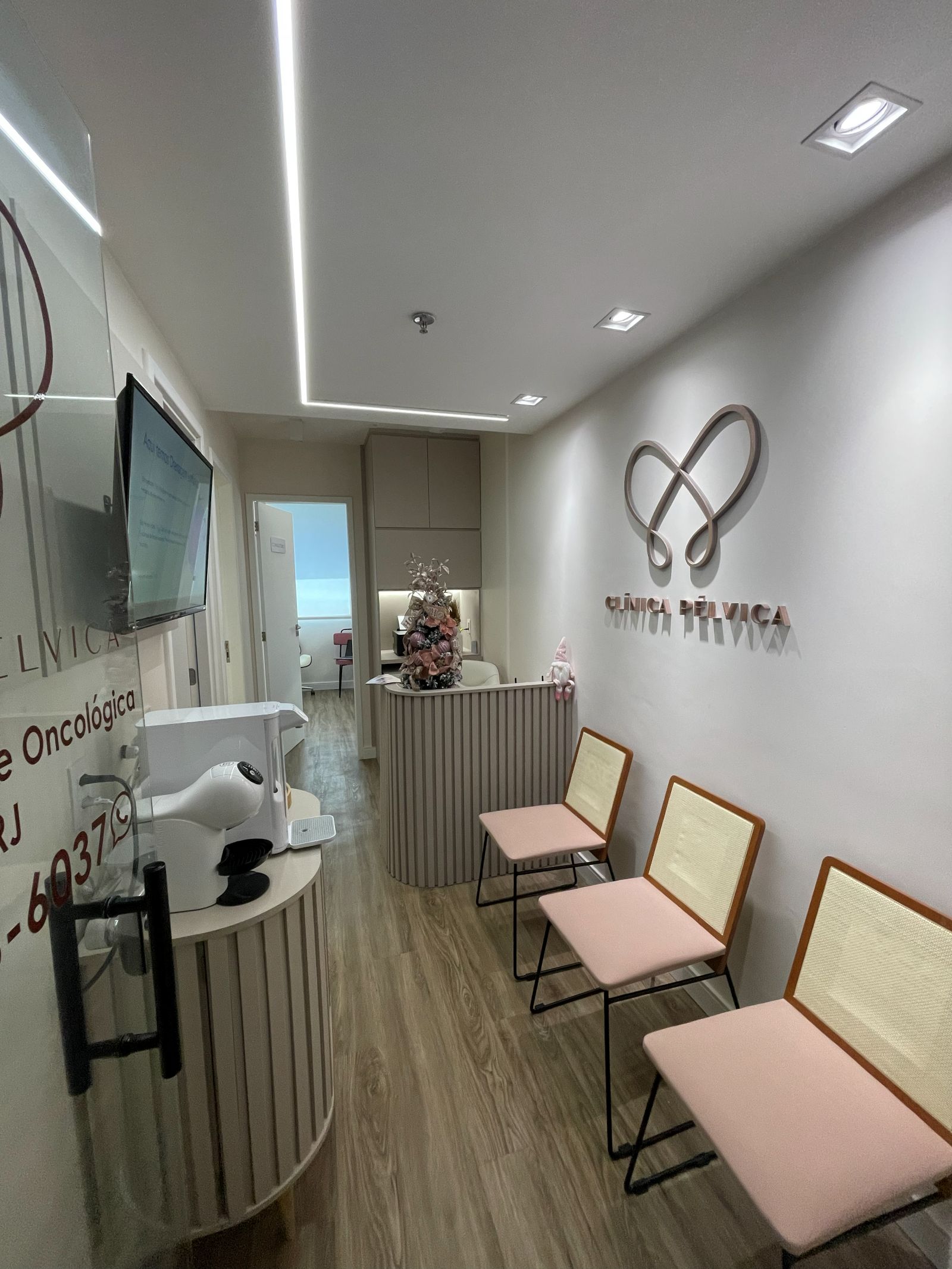 Recepção da Clínica Pélvica com o logotipo de borboleta na parede e cadeiras rosé