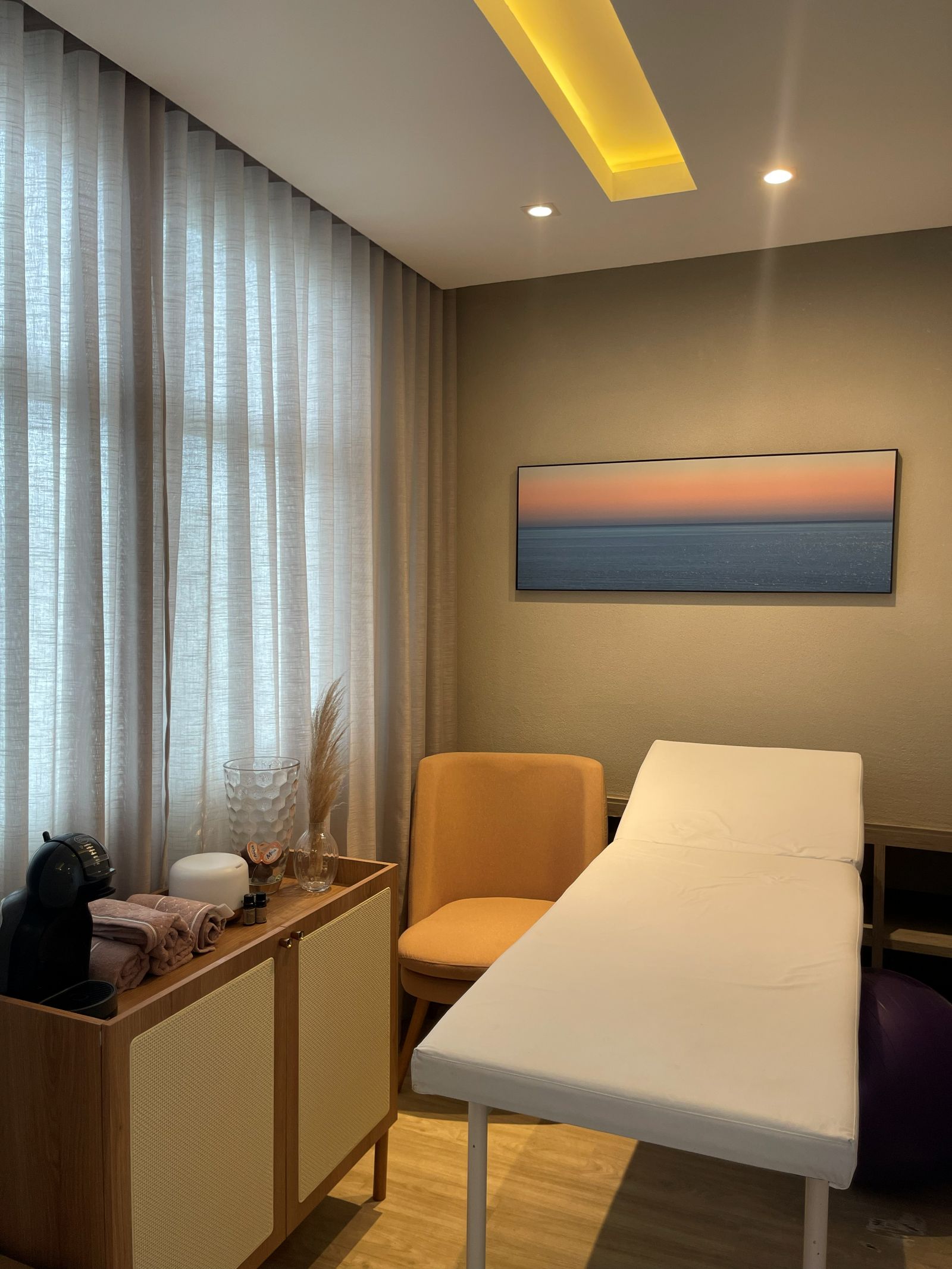 Sala de atendimento da Clínica Pélvica com maca, poltrona e quadro de paisagem