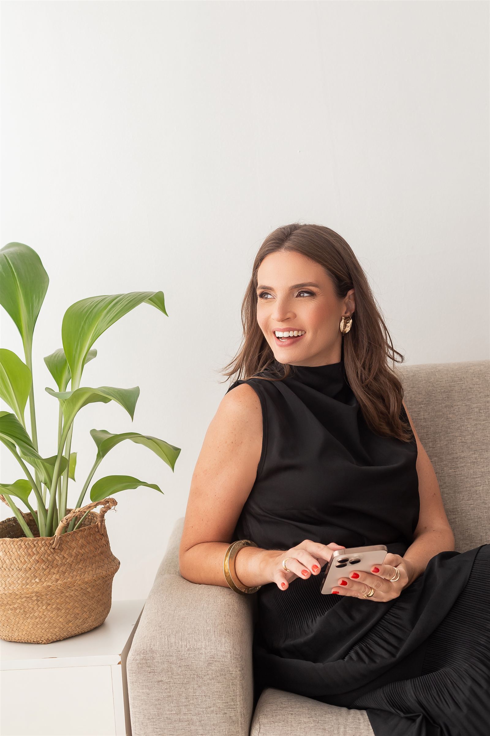 Fisioterapeuta da Clínica Pélvica sorrindo, sentada ao lado de uma planta no consultório